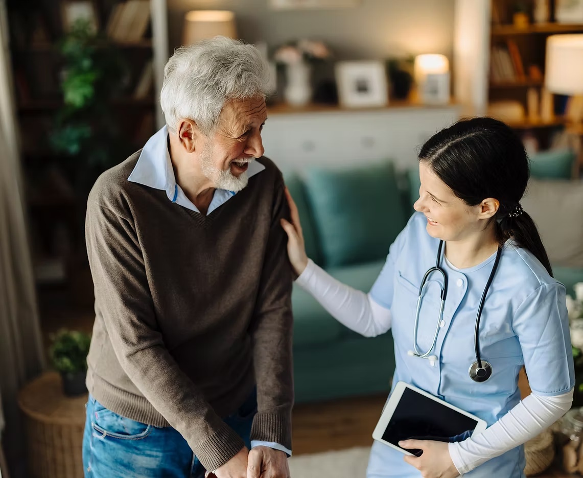 Caregiver speaking warmly with an older adult at home